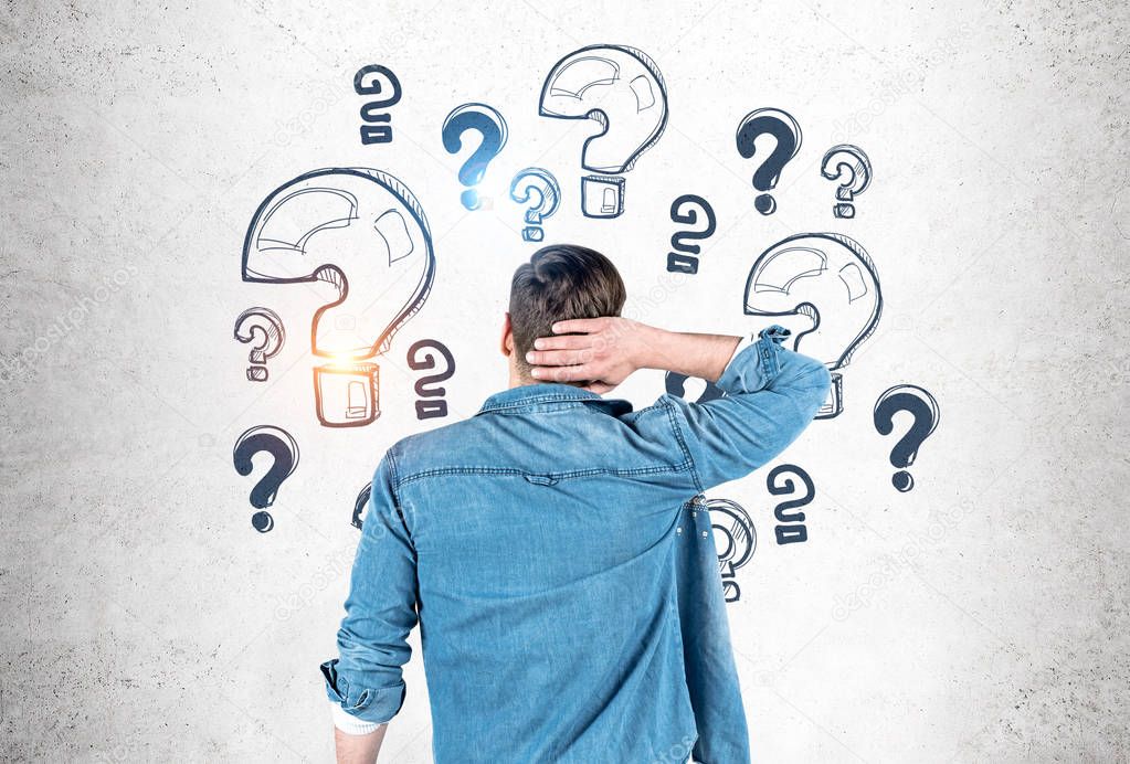 Man scratching head looking at question marks