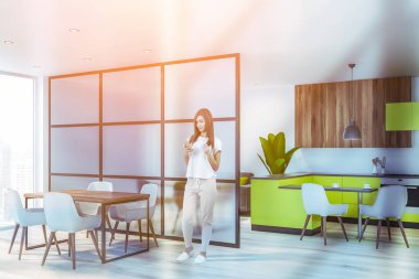 Parlak mutfağında telefonu olan bir kadın.