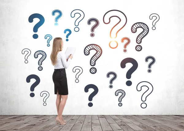 Woman with notebook looking at question marks — Stock Photo, Image