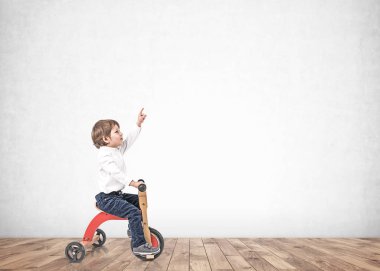 Üç tekerlekli bisikletli küçük çocuk boş odayı işaret etti