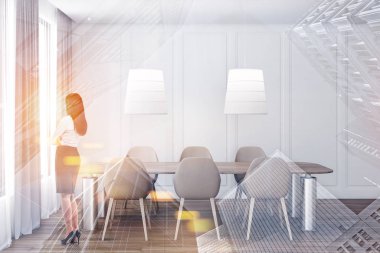 Beyaz yemek odasında duran bir kadın.