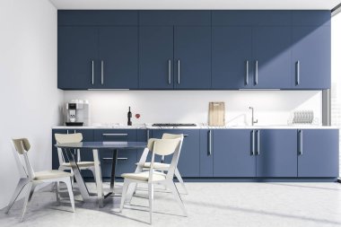 Mavi tezgahlı beyaz mutfak ve masa.