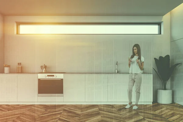 Kobieta z telefonem w białej kuchni wnętrza — Zdjęcie stockowe