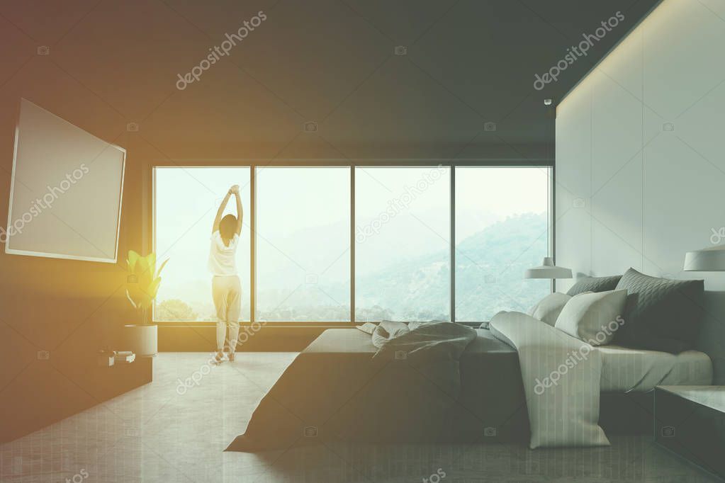 Woman in gray master bedroom with TV