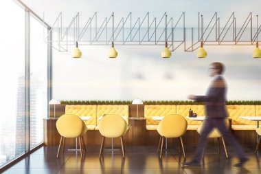 Sarı sofalarla kafede yürüyen adam