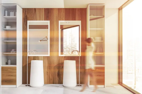 Жінка ходить в дерев'яній ванній кімнаті з двома раковинами — стокове фото