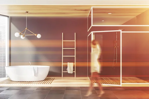 Mulher andando em banheiro cinza com banheira e chuveiro — Fotografia de Stock