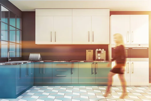 Woman walking in blue kitchen