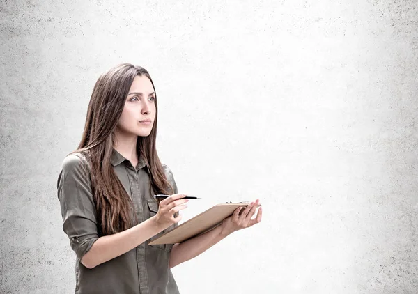 Pensive casual woman with clipboard, mock up — Stock Photo, Image
