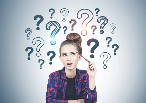 Thinking teen girl question marks on grey wall — Stock Photo, Image