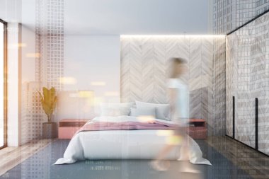 Beyaz ve hafif ahşap yatak odasında yürüyen kadın