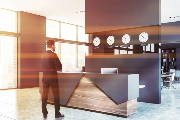 Businessman standing near gray office reception — Stock Photo, Image