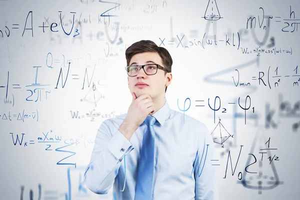 Thoughtful young man in glasses, formulas — Stock Photo, Image