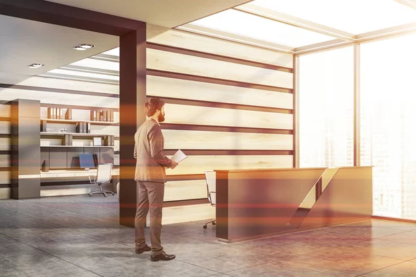 Man in gray and wooden office with reception — Stock Photo, Image