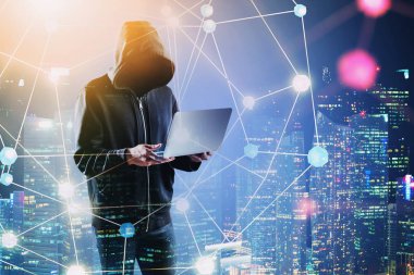 Gece şehrinde dizüstü bilgisayarı olan bir bilgisayar korsanı.