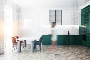 Yeşil mutfakta masa başında yürüyen bir kadın.