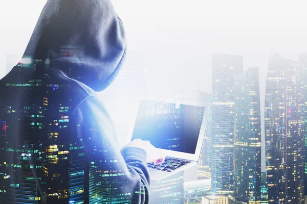 Modern şehirde dizüstü bilgisayarı olan bir bilgisayar korsanı.