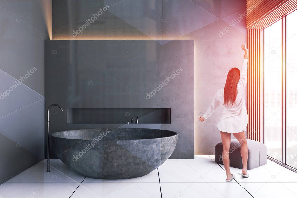 Young woman in gray luxury bathroom with stone tub