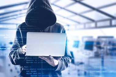 Bulanık ofiste dizüstü bilgisayarı olan bir bilgisayar korsanı