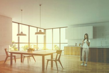 Beyaz mutfakta yemek masası olan bir kadın.