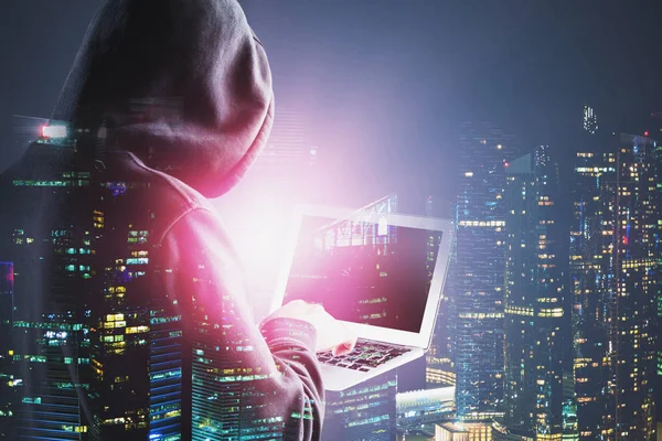 Vue arrière du pirate informatique avec ordinateur portable dans la ville de nuit — Photo