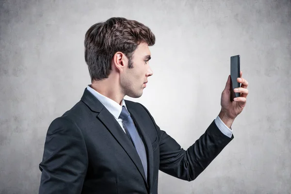 Guapo joven hombre de negocios mirando el teléfono inteligente — Foto de Stock