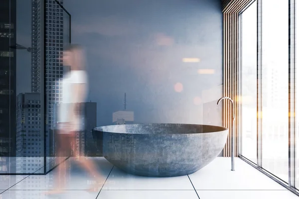 Kobieta spaceruje w szarej łazience z wanną i prysznicem — Zdjęcie stockowe