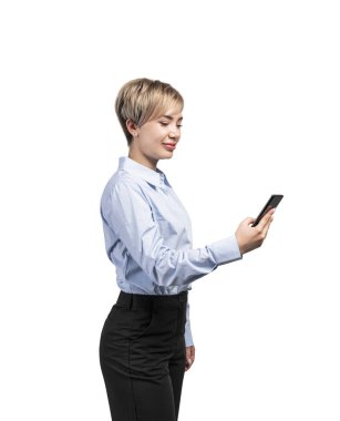 Gülümseyen genç iş kadını akıllı telefona bakıyor.