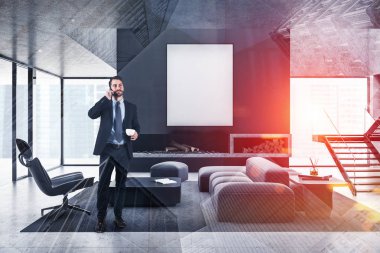 Gri oturma odasındaki şömineli ve posterli adam.