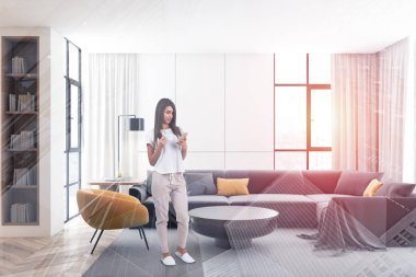 Beyaz oturma odasında telefonu olan bir kadın.