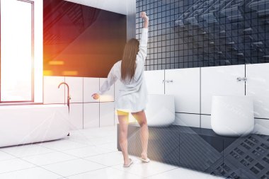 Siyah beyaz fayanslı banyo köşesindeki kadın.