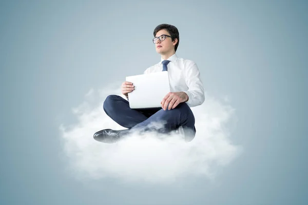 Hombre de negocios con portátil sentado en la nube —  Fotos de Stock
