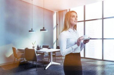 Süslü panoramik yemek odasında, mavi duvarları, halılı zemini, rahat masası ve gri koltukları olan dalgın, genç bir kadın. Tonu ayarlanmış resim