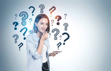 Akıllı telefondan konuşan neşeli genç kız gri duvarın yanında soru işaretleri çizilmiş. İletişim ve seçim kavramı. Model
