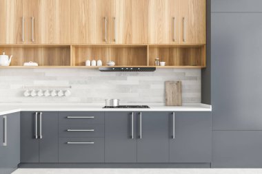 Gri ve beyaz duvarları, gri tezgahları ve ahşap dolapları olan modern mutfağın içi. 3d oluşturma