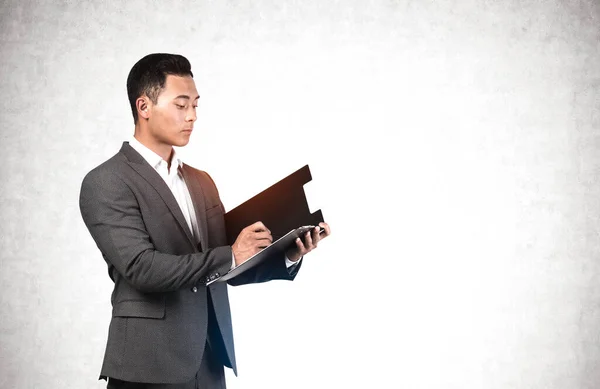 Portrait Serious Young Asian Businessman Writing Clipboard Concrete Wall Concept — Stock Photo, Image