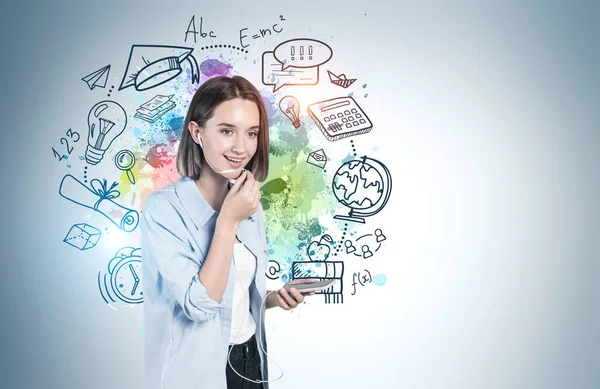 カラフルな教育スケッチが描かれた青い壁の近くのスマートフォンで話している陽気なティーンの女の子 知識の概念 モックアップ — ストック写真