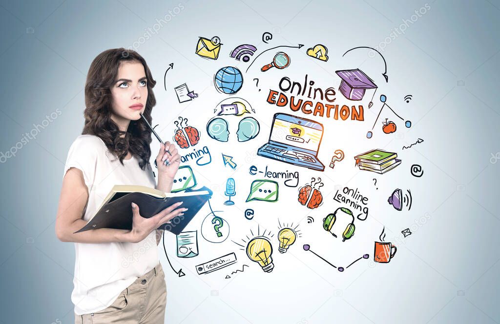 Pensive young woman in casual clothes with notebook standing near blue wall with bright online education sketch. Concept of knowledge, development and technology