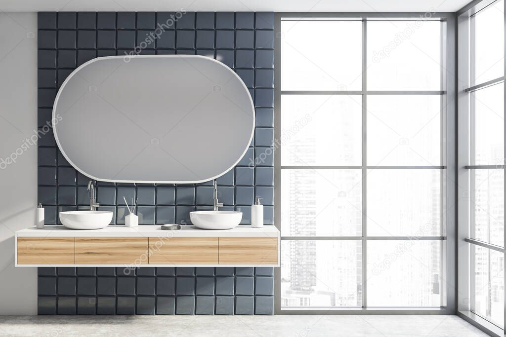 Interior of modern bathroom with white and gray tile walls, concrete floor, comfortable double sink standing on wooden countertop and oval mirror. Window with blurry cityscape. 3d rendering
