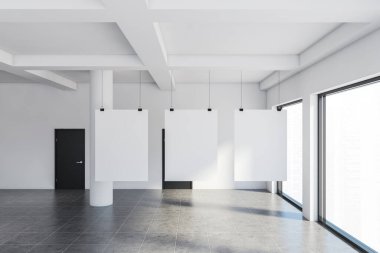 Beyaz duvarları, döşemeleri, bulanık şehir manzarası olan büyük pencereleri ve kapalı siyah kapıları olan boş sanat galerisinde asılı üç adet dikey maket poster. 3d oluşturma