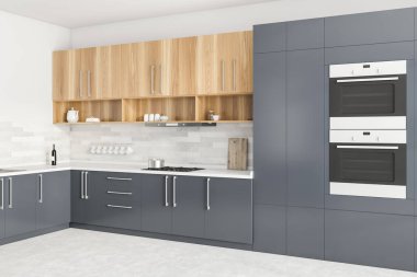 Gri ve beyaz duvarları, gri tezgahları, tahta dolapları ve iki fırını olan modern mutfağın köşesi. 3d oluşturma