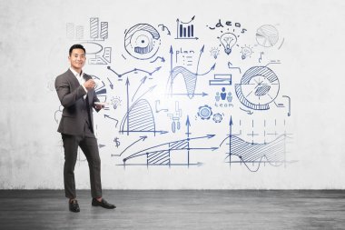 Üzerinde yaratıcı iş planı çizimi olan beton duvarın yanında duran gülümseyen Asyalı genç iş adamı. İş stratejisi geliştirme kavramı