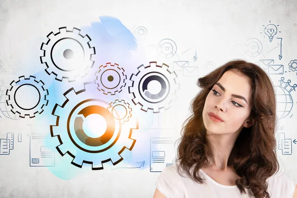 Dalgalı siyah saçlı, beton duvara çizilmiş yaratıcı viteslere bakan genç ve güzel bir iş kadını. Takım çalışması, yönetim ve planlama kavramı. Tonu ayarlanmış resim