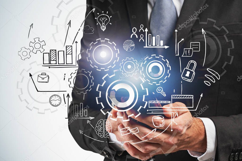 Hands of businessman holding smartphone near gray wall with double exposure of gears sketch. Concept of planning and teamwork. Toned image