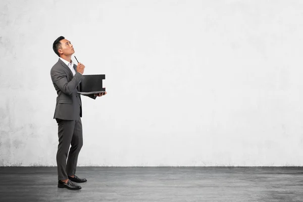 Side View Thoughtful Young Asian Businessman Clipboard Concrete Wall Room — Stock Photo, Image