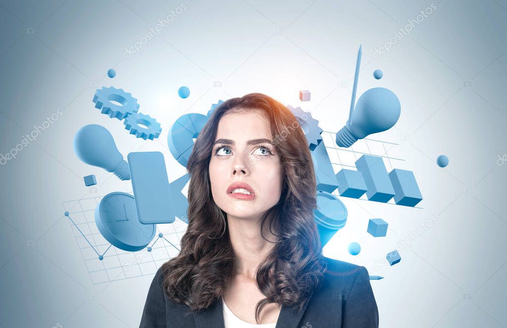 Portrait of troubled young European businesswoman standing near gray wall with business objects. Concept of business planning and education