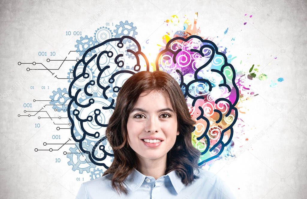 Cheerful young European woman with dark hair standing near concrete wall with colorful left and right brain sketch drawn on it. Concept of creative and analytical thinking
