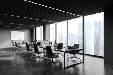 Karanlık gri duvarları, beton zemini, uzun bilgisayar tabloları, yatay maket posterleri ve bulanık şehir manzaralı pencereleri olan panoramik açık uzay ofisindeki modern işyeri. 3d oluşturma