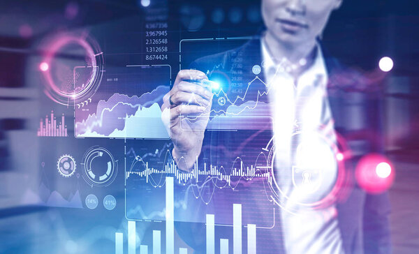 Unrecognizable young businesswoman using immersive HUD business infographic interface in blurry office. Concept of big data and hi tech. Toned image