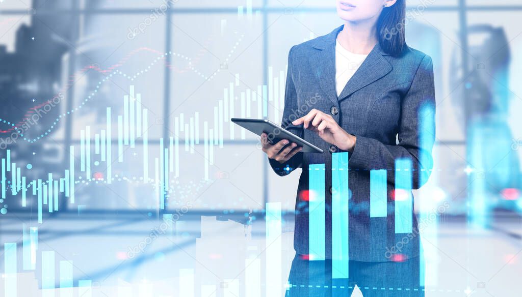 Unrecognizable young businesswoman using her tablet in blurry panoramic Moscow city office with double exposure of digital graphs. Concept of trading and investment. Toned image